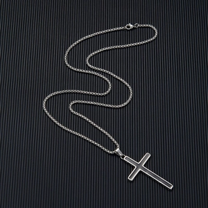 Close-up of silver stainless steel cross pendant with black inlay on a box chain