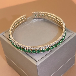 Detail of double-row gold-plated cuff bracelet featuring green and white zirconia pavé