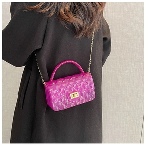Detail of rose red jelly bag with quilted texture, gold chain and beaded handle