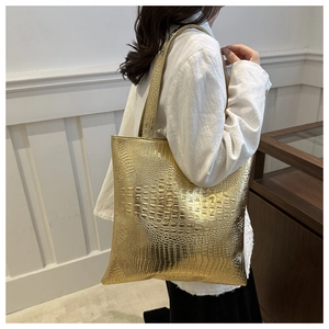 Detail of golden crocodile embossed tote bag with high-shine metallic texture finish