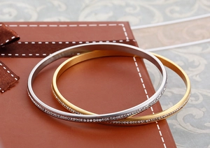 Dettaglio di bracciali placcati oro e argento con strass su una scatola regalo