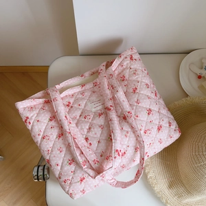 Detailed macro of pink floral quilted cotton fabric with a white woven label on tote bag