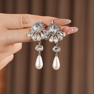 Close-up of vintage flower earrings with crystal accents and white teardrop pearls