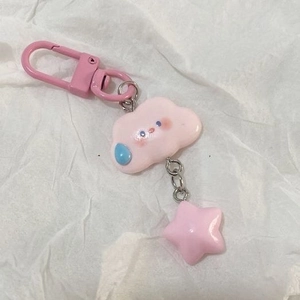 Detail of pink resin cloud keychain with star pendant on a white textured background