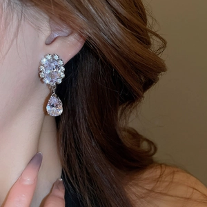 Macro detail of sparkling water-drop zircon pendant earring worn on a model's ear