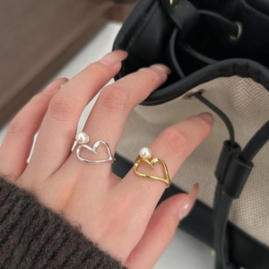 Detail of minimalist S925 silver and gold heart rings with pearls worn by a model