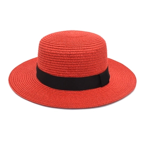 Detail view of red boater straw hat with black ribbon and woven texture