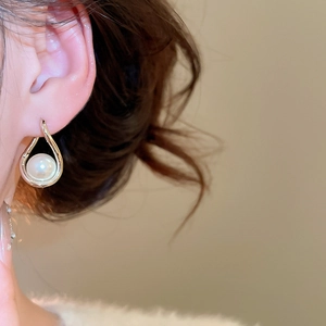 Gros plan de boucles d'oreilles dorées goutte d'eau avec perle blanche sur l'oreille femme