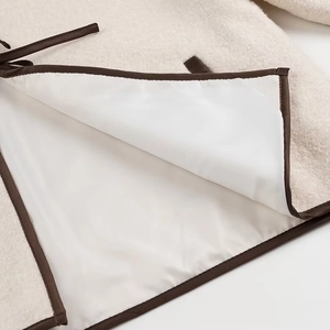 Detailopname van beige fleece stof met bruine contrastbies en hoogwaardige afwerking