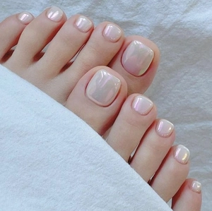 Close-up of pearlescent white press-on toenails with shell finish on a white towel