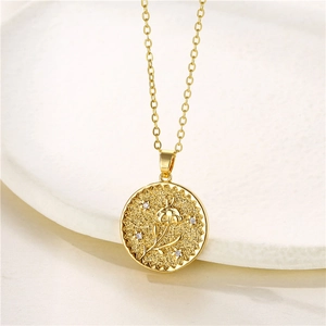 Macro detail of gold coin pendant featuring embossed flower and star motifs with zircons