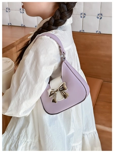 Detail of lavender PU leather crossbody bag featuring a 3D silver bow and shoulder strap