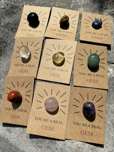 Macro view of 9 natural healing crystal gems on kraft cards with 'You're a Real Gem' text