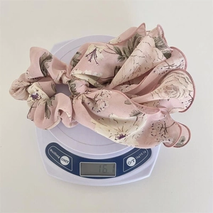 Détail d'un chouchou en mousseline rose à fleurs pesant 16,1g sur une balance