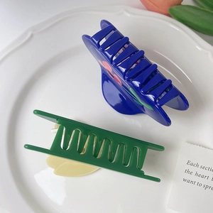 Close-up of floral acetate claw clips in blue and green on a ceramic tray display