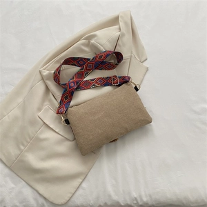 Detailed shot of beige woven bag featuring a colorful ethnic style geometric shoulder strap