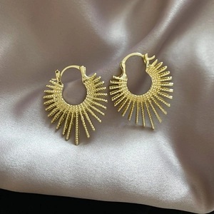 Macro view of gold sunburst earrings with spiral texture on satin background