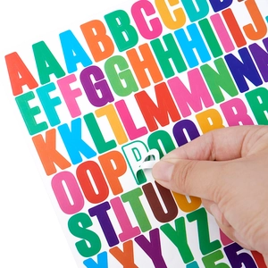 Close-up of peeling a green vinyl letter sticker from a colorful alphabet sheet