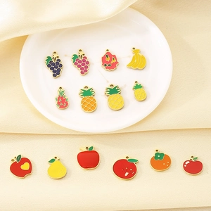 Close-up of colorful enamel fruit pendants in apple and pineapple shapes for DIY jewelry