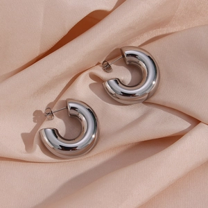 Polished silver chunky hoop earrings on champagne silk fabric background