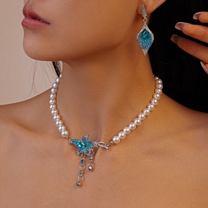Close-up of pearl necklace and earring set featuring blue flower and star charms