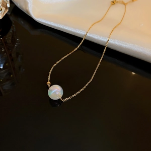 Macro shot of gold fishtail necklace with iridescent white opal pearl pendant detail