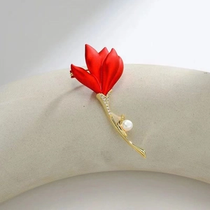 Macro detail of red matte flower brooch with pearl accent and sparkling crystals