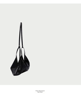 Detailed close-up showing the 3D geometric folds and texture of the black leather bag