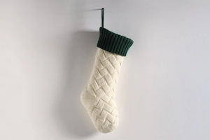 Detail of cable knit Christmas stocking in cream with dark green ribbed cuff decoration