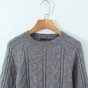 Detailed knit texture and inner collar label of a grey backless cable-knit sweater