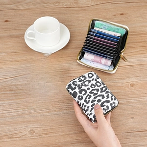 Leopard print accordion card holder and wallet with zipper on a wooden table