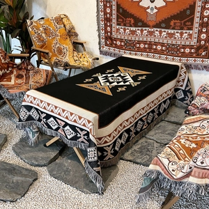 Bohemian geometric outdoor picnic blanket with decorative tassels in a campsite setting