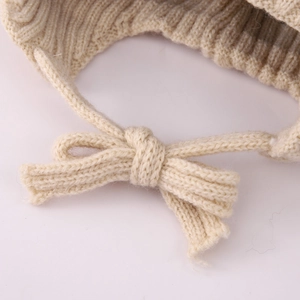 Macro detail of soft knit cord tied in a bow on a beige winter bear hat for kids