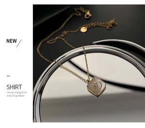 Macro shot of gold square necklace with shell inlay and smiling face on mirror surface