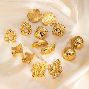 Detail of vintage gold-plated earrings with hammered texture on elegant silk fabric