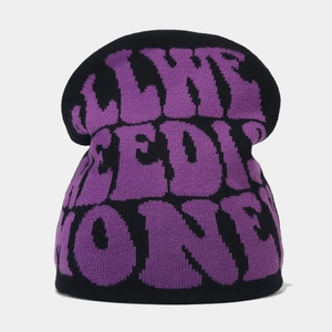 Close-up of Y2K knit beanie featuring purple jacquard text on a black wool surface