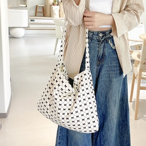 Detail of off-white canvas tote bag featuring stylish black bow prints and wide strap