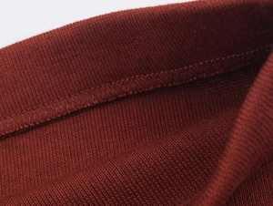 Vue macro de la texture en maille rouge rouille avec détail d'ourlet cousu professionnel