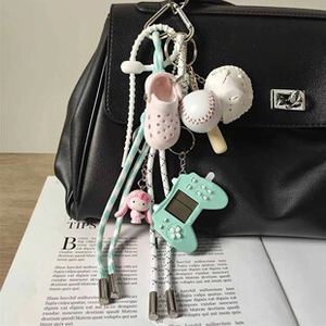 Dettaglio di ciondoli da baseball e scarpe su una borsa elegante in pelle nera