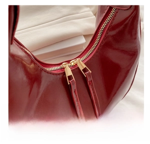 Macro detail of the smooth metal dual zippers on this chic burgundy crescent handbag
