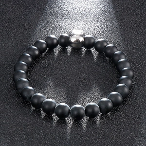 Macro shot of 8mm matte black beads and silver skull charm on a dark leather texture