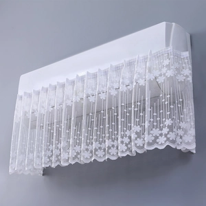 Detail of white lace air conditioner cover with delicate floral embroidery on gray background