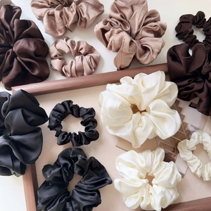 Detail of assorted silk satin scrunchies in earth tones on a rustic wooden frame