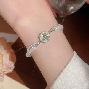 Zweilagiges Perlenarmband mit funkelndem silbernem Sternanhänger am Handgelenk getragen