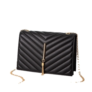 Black quilted crossbody bag with gold chain strap and tassel detail on white background