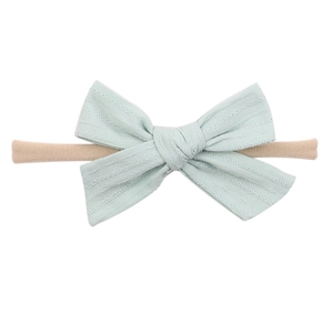 Close-up of soft light blue fabric bow headband with detailed jacquard texture for babies