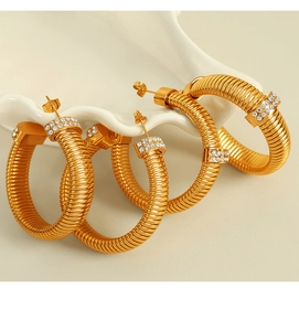 Macro shot of gold spiral earrings featuring intricate pave set crystals on metal surface