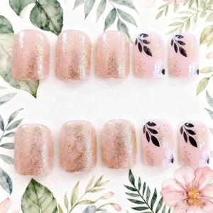 Short square press-on nails with pink base, gold glitter, and delicate floral leaf patterns