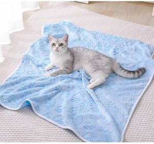Soft light blue flannel pet blanket with paw prints shown with a cat in a cozy home setting