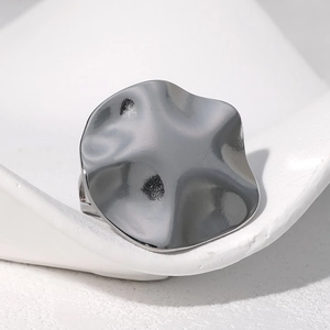 Minimalist silver wavy stainless steel ring displayed on a modern white stone tray